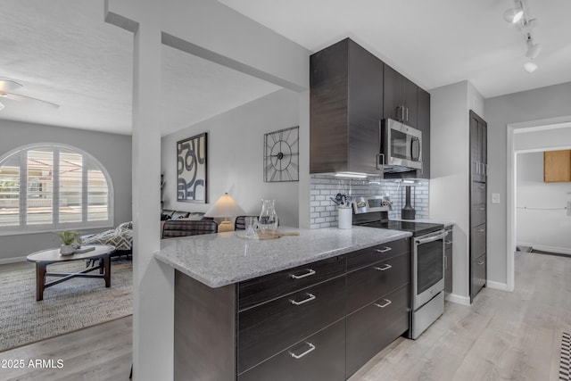 kitchen with decorative backsplash, appliances with stainless steel finishes, light stone countertops, dark brown cabinets, and light wood-style floors