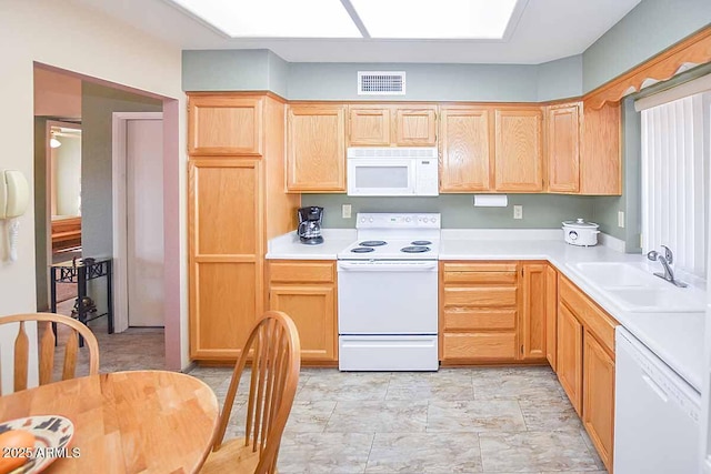 kitchen with white appliances, light brown cabinetry, and sink