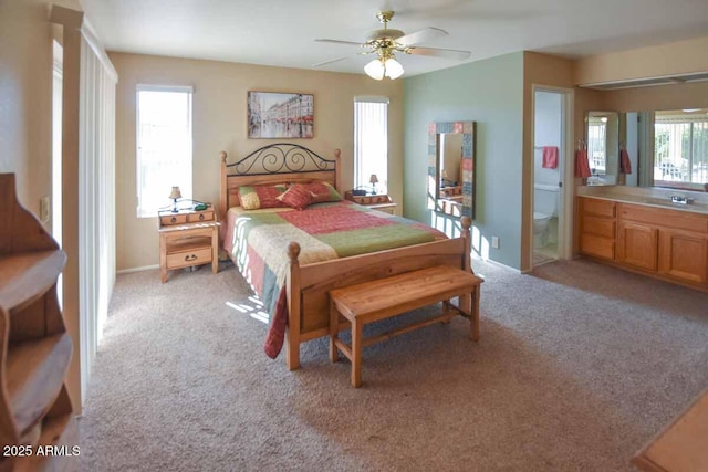 bedroom with connected bathroom, light colored carpet, and ceiling fan