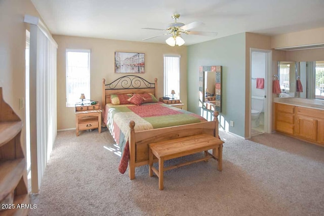 bedroom with connected bathroom, light colored carpet, and ceiling fan