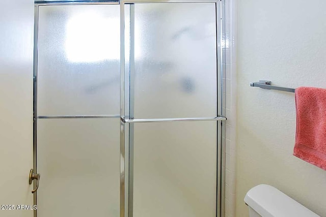 bathroom with a shower with door and toilet