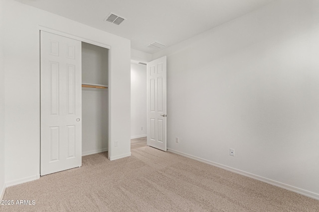 unfurnished bedroom with light colored carpet and a closet