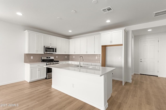 kitchen featuring sink, white cabinetry, a kitchen island with sink, and appliances with stainless steel finishes