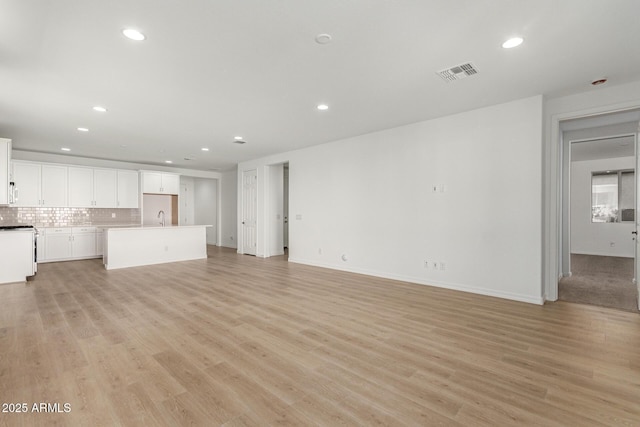 unfurnished living room featuring sink and light hardwood / wood-style floors