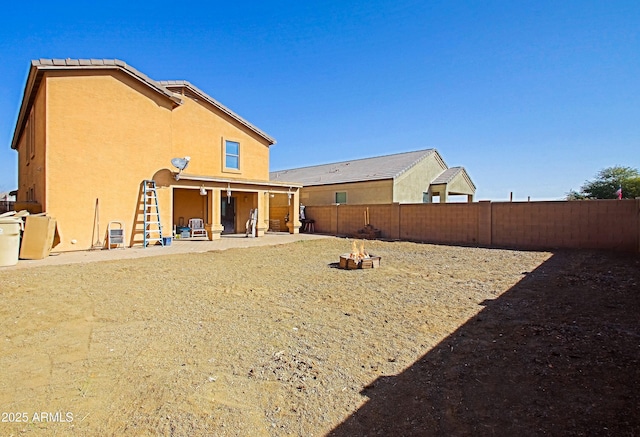 back of property with a patio and an outdoor fire pit