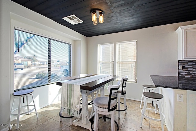 tiled dining room featuring plenty of natural light and wood ceiling