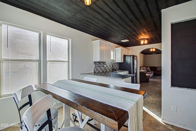 dining area featuring dark tile patterned floors, sink, and wooden ceiling