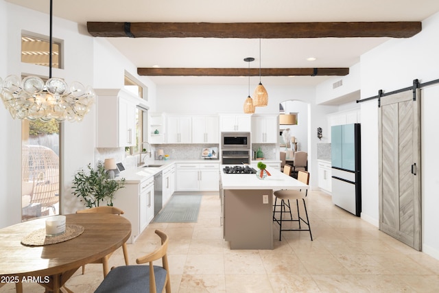 kitchen featuring decorative light fixtures, appliances with stainless steel finishes, a kitchen island, a barn door, and white cabinets