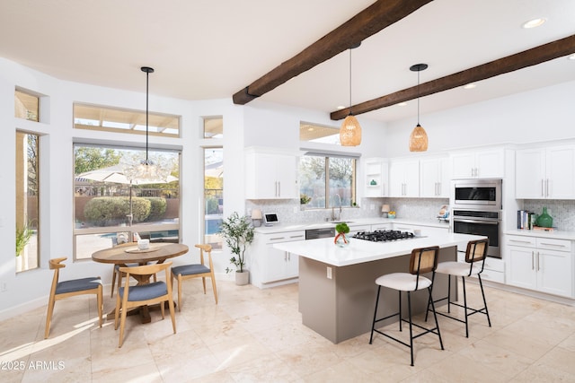 kitchen with stainless steel appliances, a kitchen island, hanging light fixtures, and white cabinets