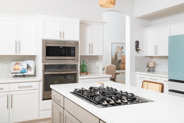 kitchen with backsplash, white cabinets, and appliances with stainless steel finishes