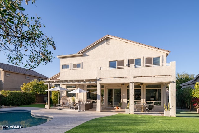 back of house featuring a patio, a balcony, an outdoor hangout area, a yard, and ceiling fan