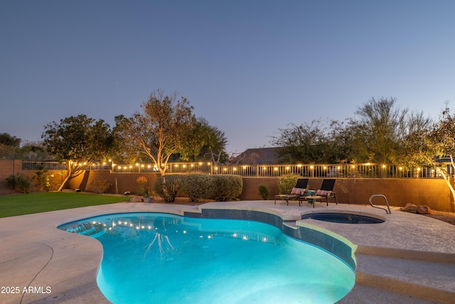 pool at dusk with an in ground hot tub and a patio