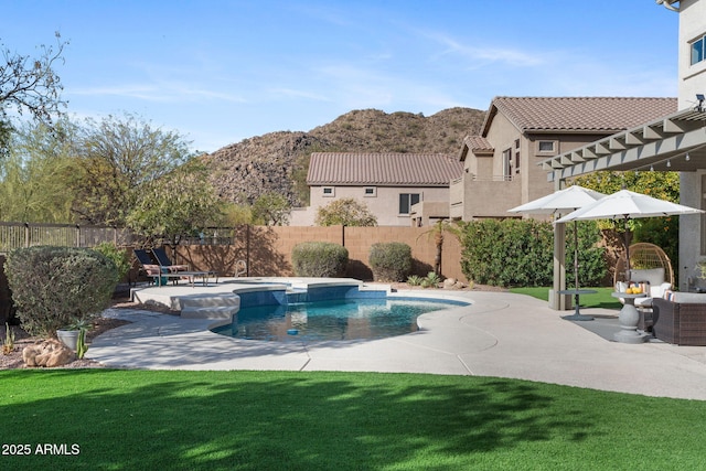 view of swimming pool featuring a patio, a mountain view, and a lawn