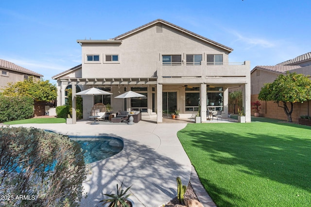 rear view of property with a patio area, a balcony, a yard, outdoor lounge area, and ceiling fan