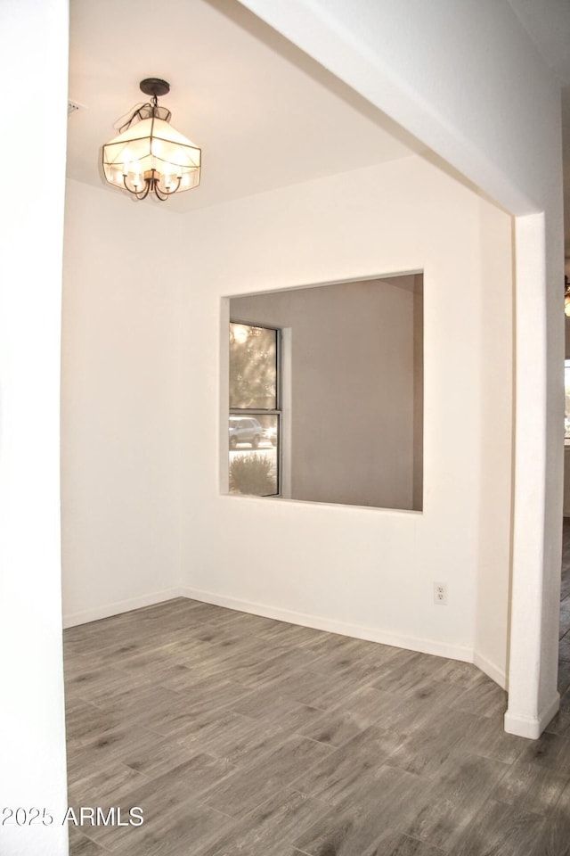 unfurnished room with an inviting chandelier and dark hardwood / wood-style flooring