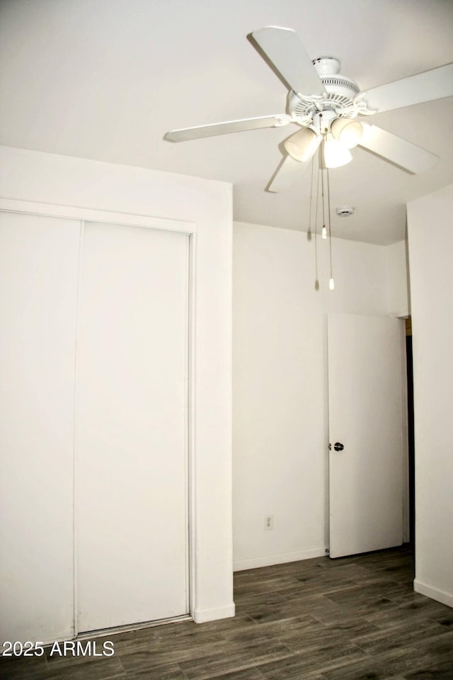 unfurnished bedroom featuring dark wood-type flooring, ceiling fan, and a closet