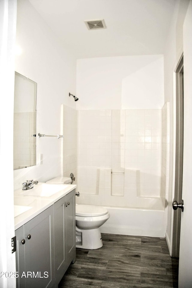 full bathroom featuring toilet, hardwood / wood-style flooring, bathtub / shower combination, and vanity