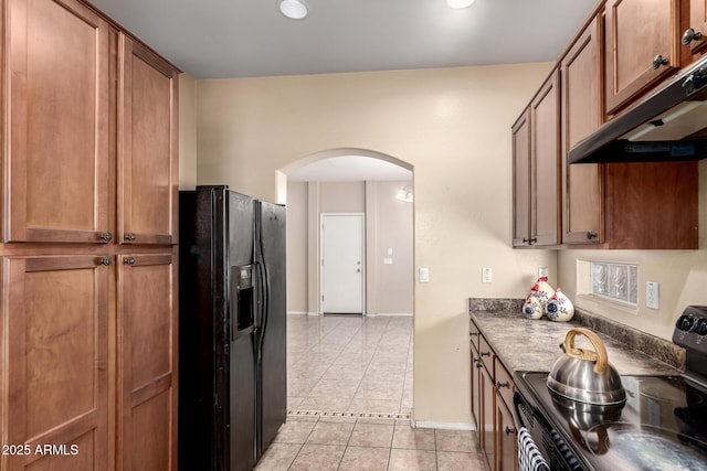 10 N 87th Dr, Tolleson, AZ 85353 - kitchen featuring black appliances, arched walkways, under cabinet range hood, light tile patterned flooring, and brown cabinetry