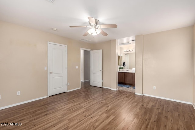 10 N 87th Dr, Tolleson, AZ 85353 - unfurnished bedroom featuring wood finished floors, baseboards, ensuite bathroom, and a ceiling fan