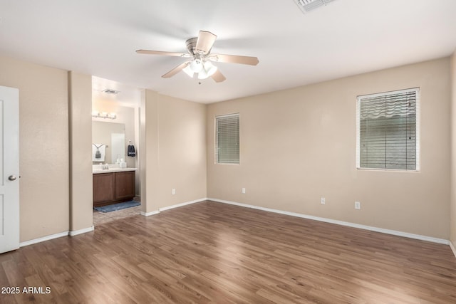 10 N 87th Dr, Tolleson, AZ 85353 - unfurnished bedroom with wood finished floors, baseboards, connected bathroom, and a ceiling fan