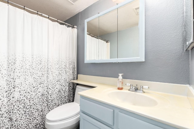 bathroom featuring a textured ceiling, vanity, toilet, a textured wall, and a shower with shower curtain