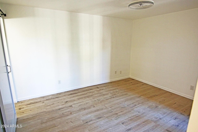 empty room featuring light hardwood / wood-style floors and a barn door