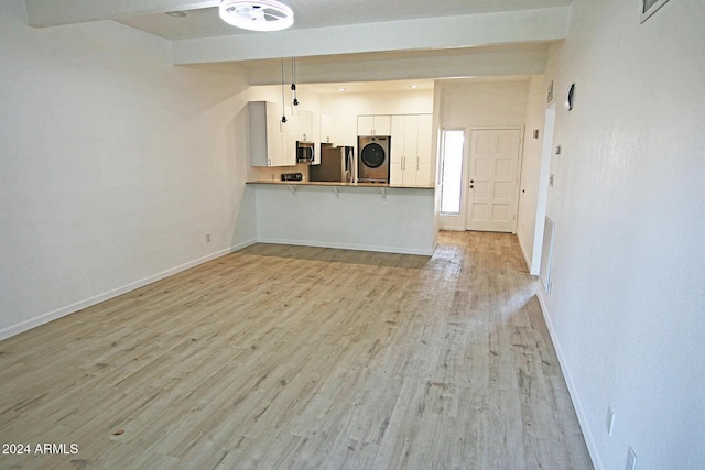 unfurnished living room featuring light hardwood / wood-style floors, beam ceiling, and stacked washer and dryer