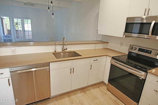 kitchen with appliances with stainless steel finishes, white cabinetry, and sink