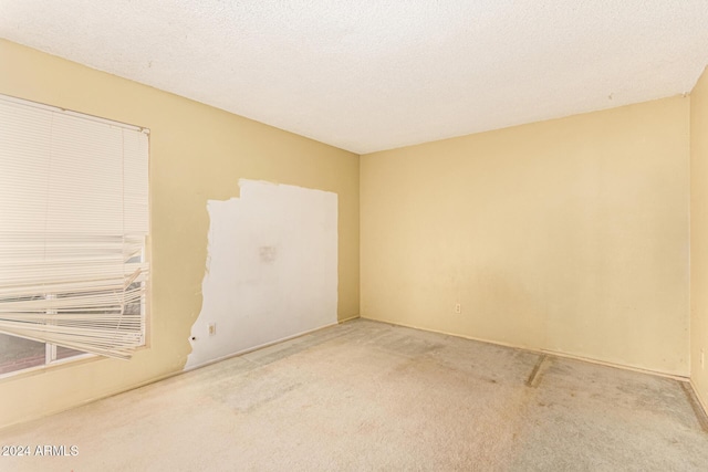 carpeted empty room featuring a textured ceiling