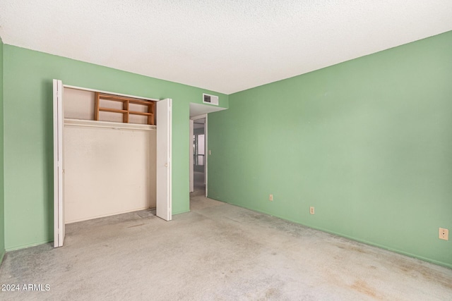 unfurnished bedroom with light carpet, a textured ceiling, and a closet