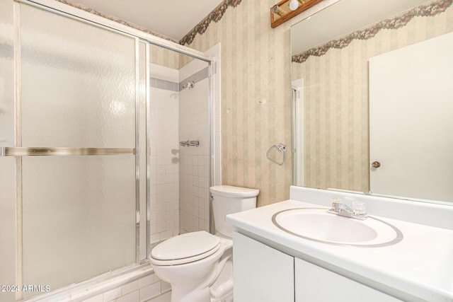 bathroom with vanity, toilet, and a shower with shower door