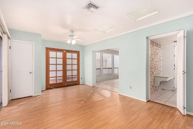 empty room with ceiling fan, light hardwood / wood-style floors, and french doors