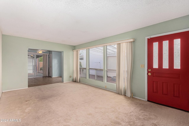 entryway featuring carpet flooring, a textured ceiling, a wealth of natural light, and ceiling fan