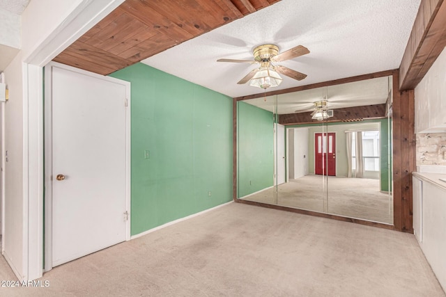 interior space featuring ceiling fan, beam ceiling, light colored carpet, and a textured ceiling