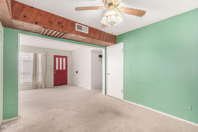 carpeted empty room with ceiling fan and a textured ceiling