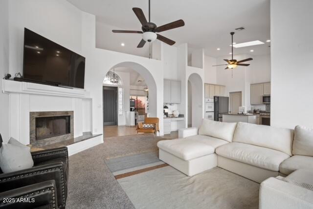 carpeted living room with ceiling fan and a towering ceiling