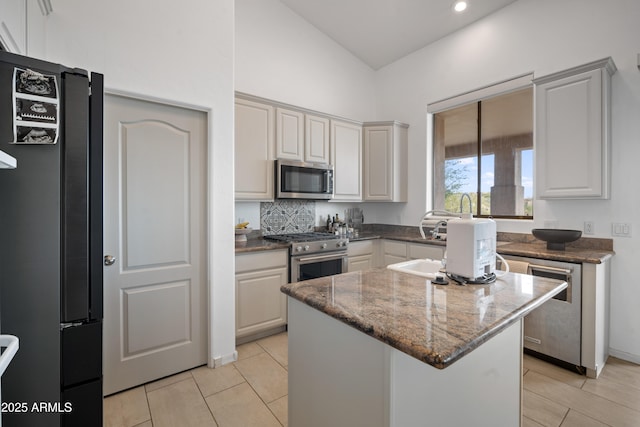 kitchen with appliances with stainless steel finishes, stone counters, white cabinetry, and a kitchen island