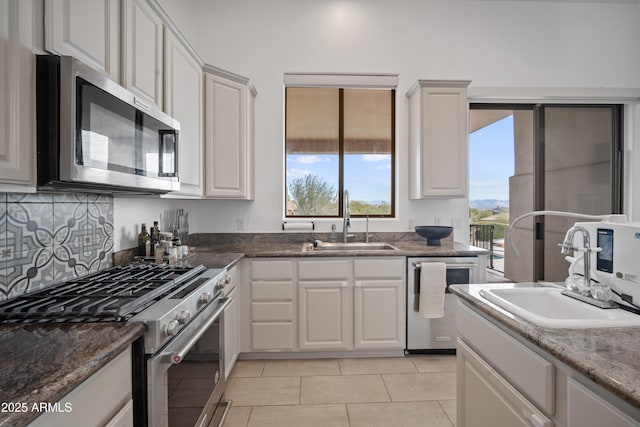 kitchen with light tile patterned floors, sink, stainless steel appliances, and white cabinetry