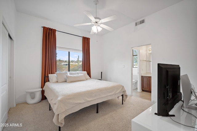 bedroom with ceiling fan, connected bathroom, a closet, and light carpet