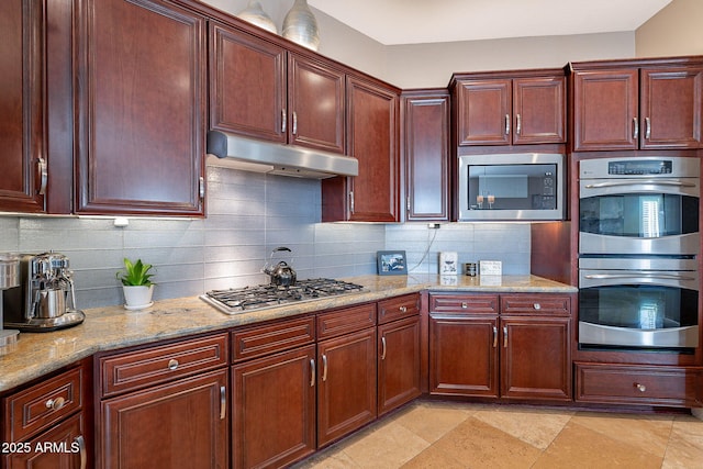 kitchen with appliances with stainless steel finishes, light stone countertops, and decorative backsplash