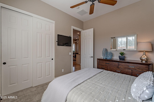 bedroom with light colored carpet, ceiling fan, and a closet