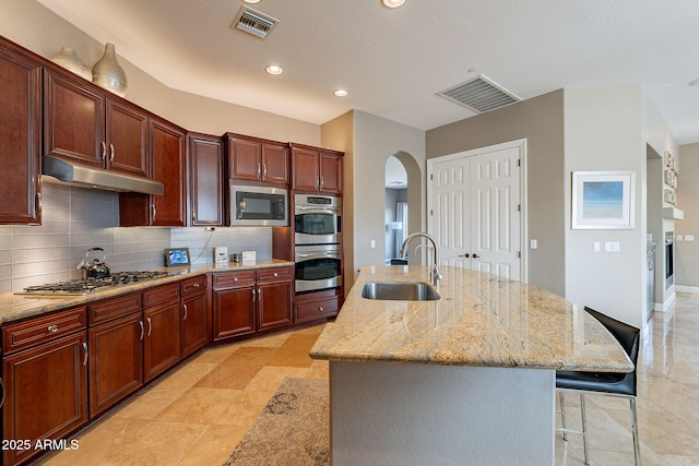 kitchen featuring an island with sink, sink, backsplash, a kitchen bar, and stainless steel appliances