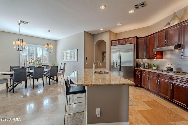 kitchen with an island with sink, appliances with stainless steel finishes, sink, and decorative backsplash