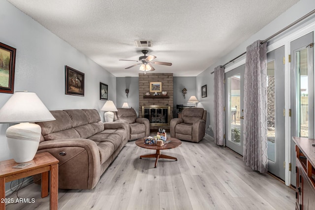 5221 W Garden Dr, Glendale, AZ 85304 - living area with a fireplace, light wood-style flooring, a textured ceiling, a ceiling fan, and visible vents