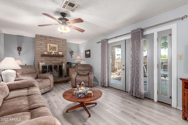 5221 W Garden Dr, Glendale, AZ 85304 - living area featuring light wood-style floors, ceiling fan, a textured ceiling, a large fireplace, and visible vents