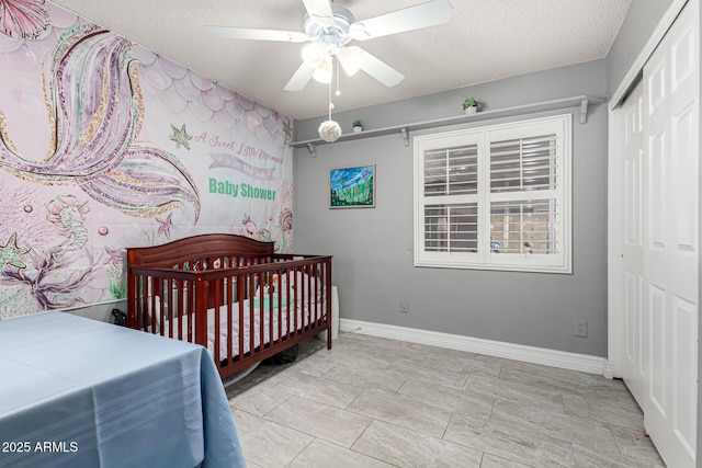 5221 W Garden Dr, Glendale, AZ 85304 - bedroom with a crib, baseboards, a closet, and a textured ceiling