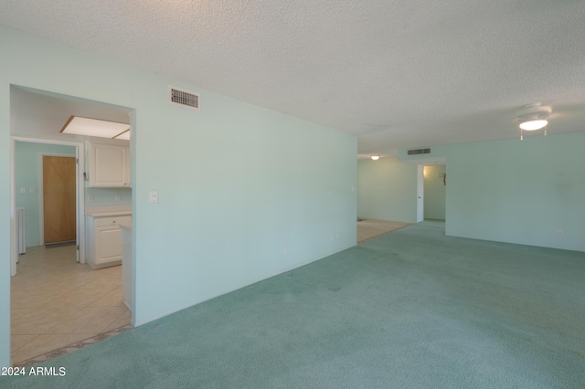 empty room featuring light carpet, a textured ceiling, and visible vents