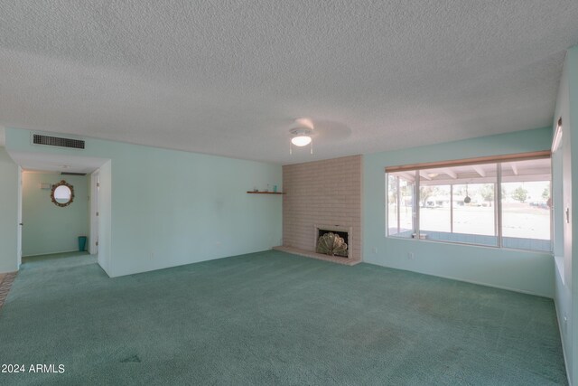 unfurnished living room with carpet floors, a brick fireplace, visible vents, and a textured ceiling