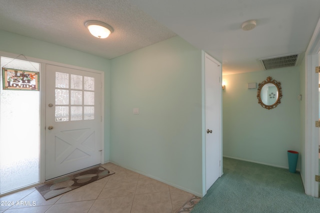 doorway to outside with a healthy amount of sunlight, visible vents, a textured ceiling, and light tile patterned floors