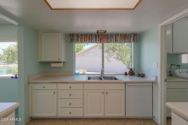 kitchen with light tile patterned floors, light countertops, a sink, and white cabinets